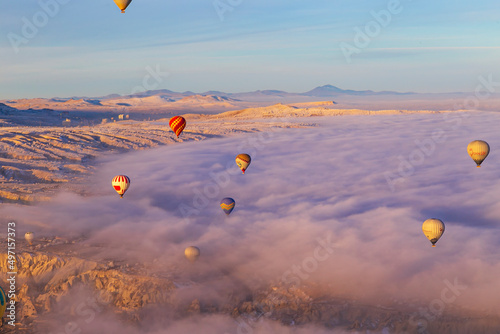 Hot air balloons flying over Cappadocia Goreme National Park Turkey with a view Erciyes mountain  foggy air © Birol
