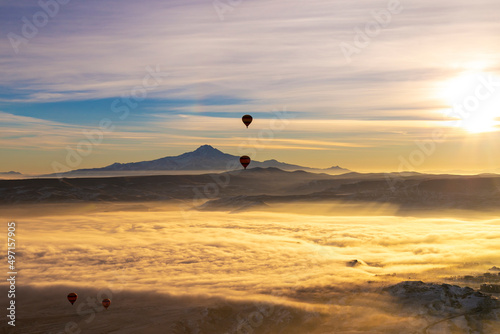 Hot air balloons flying over Cappadocia Goreme National Park Turkey with a view Erciyes mountain; foggy air