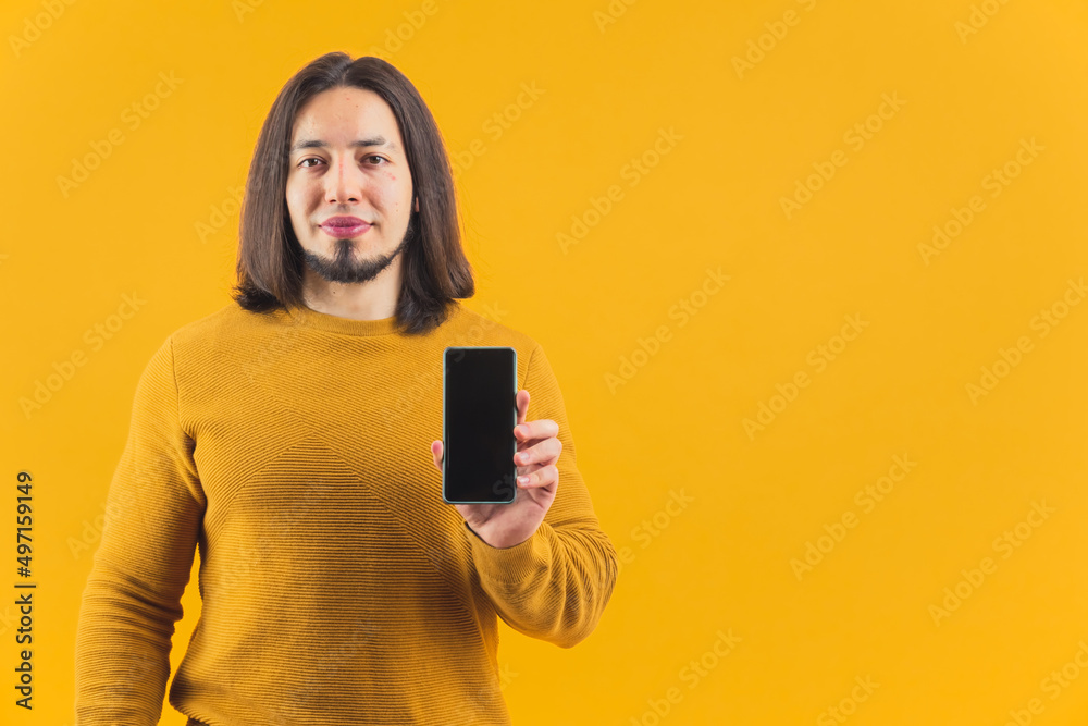 Half length shot of optimistic man holding his smartphone with mock up black screen over yellow background. High quality photo Half length shot of optimistic man holding his smartphone with mock up black screen over yellow background. High quality photo