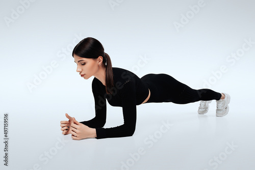 Attractive young woman does plank exercise in gym. Isolated photo