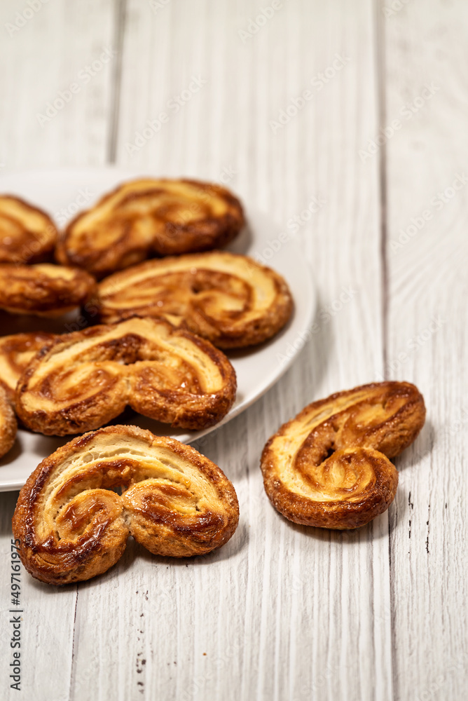 Palmier puff pastry biscuits in white plate on a white painted wooden table
Palmier puff pastry biscuits in white plate on a white painted wooden table