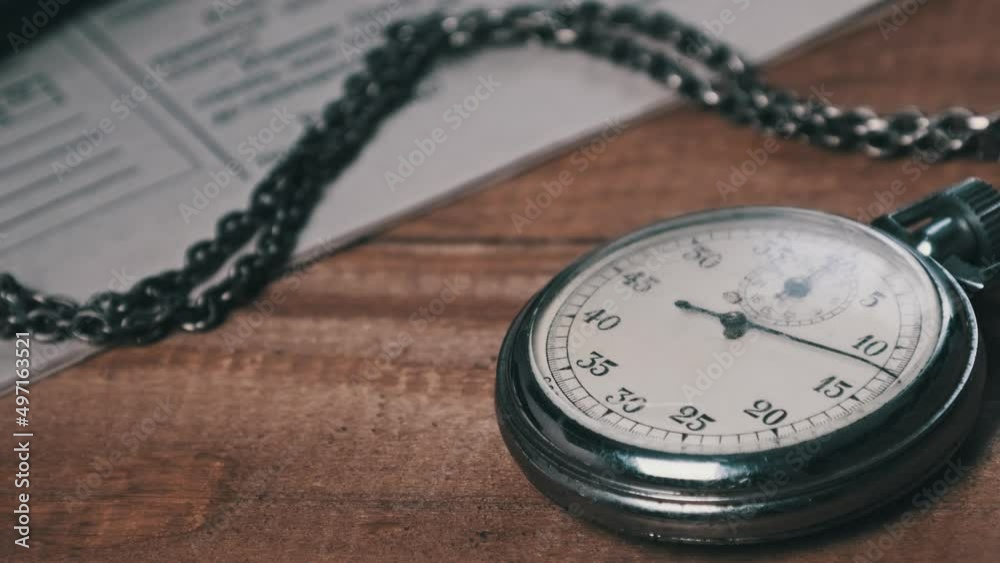 Vintage stopwatch lies on wooden writing desk with retro documents and