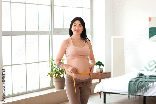 Young pregnant woman measur...