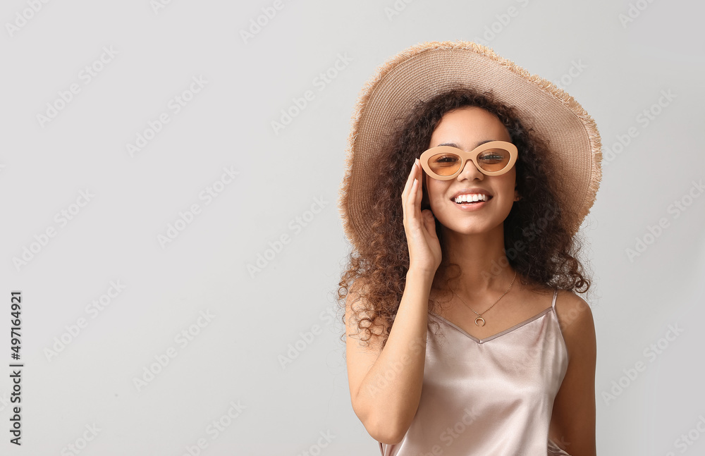 Beautiful African-American woman in broad brim hat on light background Beautiful African-American woman in broad brim hat on light background