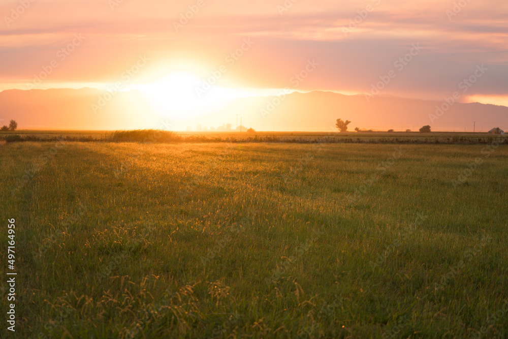 sunset over a farm barn and agricultural fields