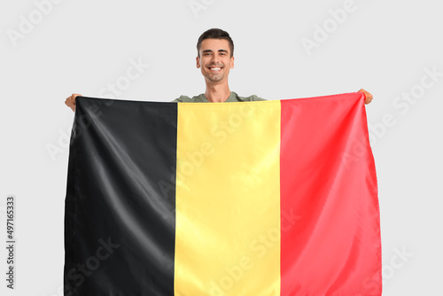 Young man with flag of Belgium on light background