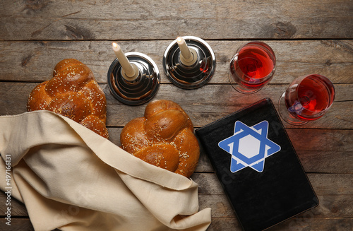 Torah with traditional challah bread, glasses of wine and candles on wooden background. Shabbat Shalom photo