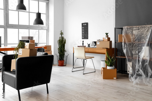 Cardboard boxes with belongings and furniture in interior of office on moving day © Pixel-Shot