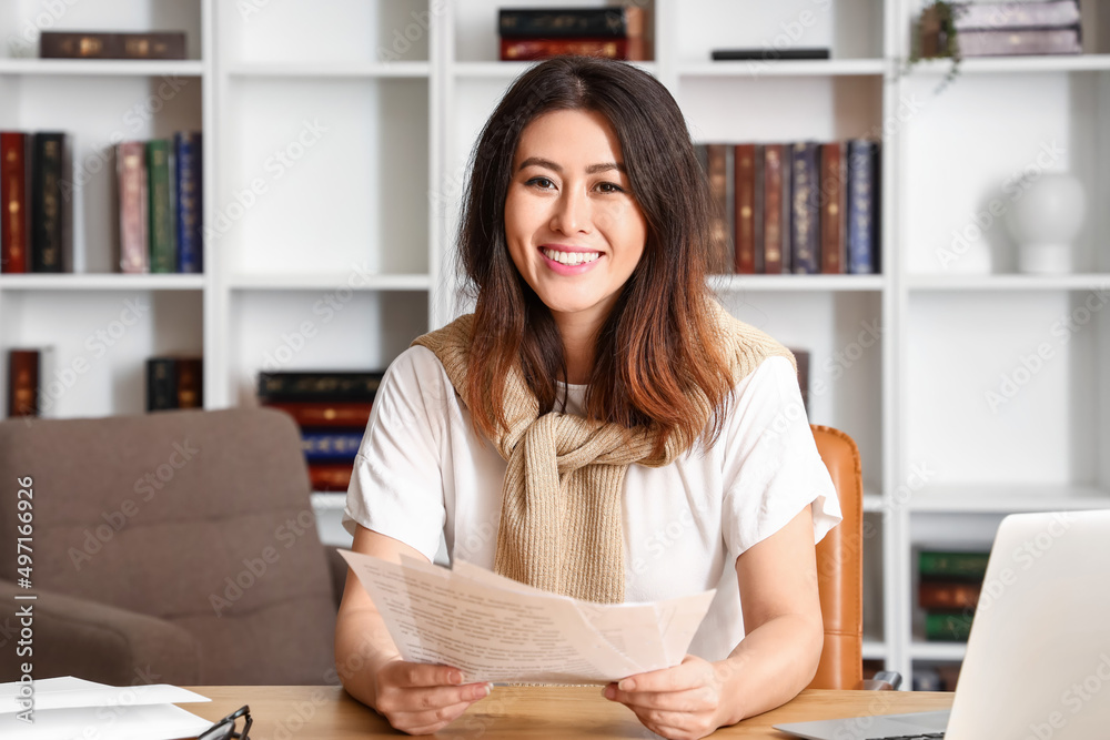 Young Asian tutor with paper sheets giving lesson online at home Young Asian tutor with paper sheets giving lesson online at home