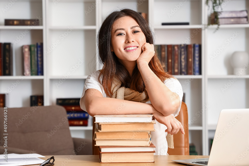 Young Asian tutor with books sitting at home Young Asian tutor with books sitting at home
