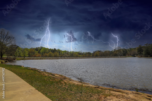 a vast rippling lake in the park surrounded by lush green trees with powerful storm clouds in the sky with lightning at Murphey Candler Park in Atlanta Georgia USA photo