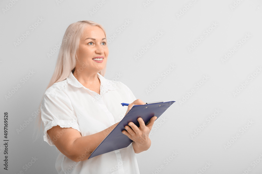 Mature secretary with clipboard on light background Mature secretary with clipboard on light background