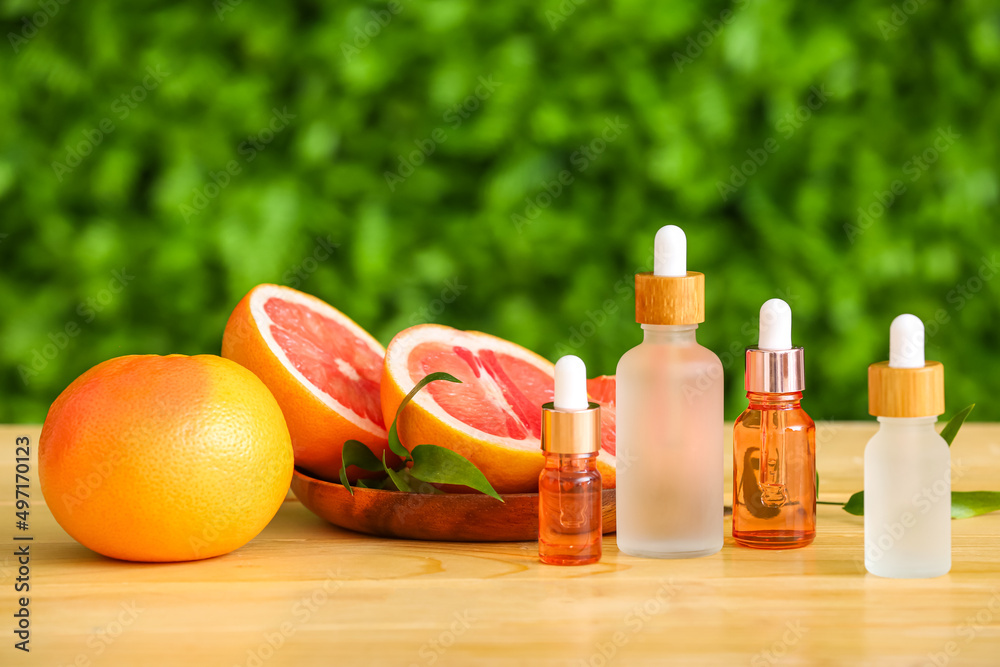 Bottles of essential oil and ripe grapefruits on wooden table outdoors Bottles of essential oil and ripe grapefruits on wooden table outdoors