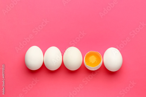 Cracked and whole chicken eggs on pink background. Concept of uniqueness