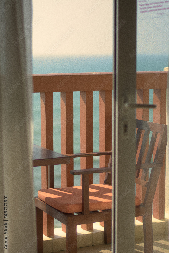 lounge chair and table on high rise apartment hotel balcony near the seaside with ocean view in Sri Lanka, outdoor furniture and architecture with orange concrete rail and sliding glass door lounge chair and table on high rise apartment hotel balcony near the seaside with ocean view in Sri Lanka, outdoor furniture and architecture with orange concrete rail and sliding glass door