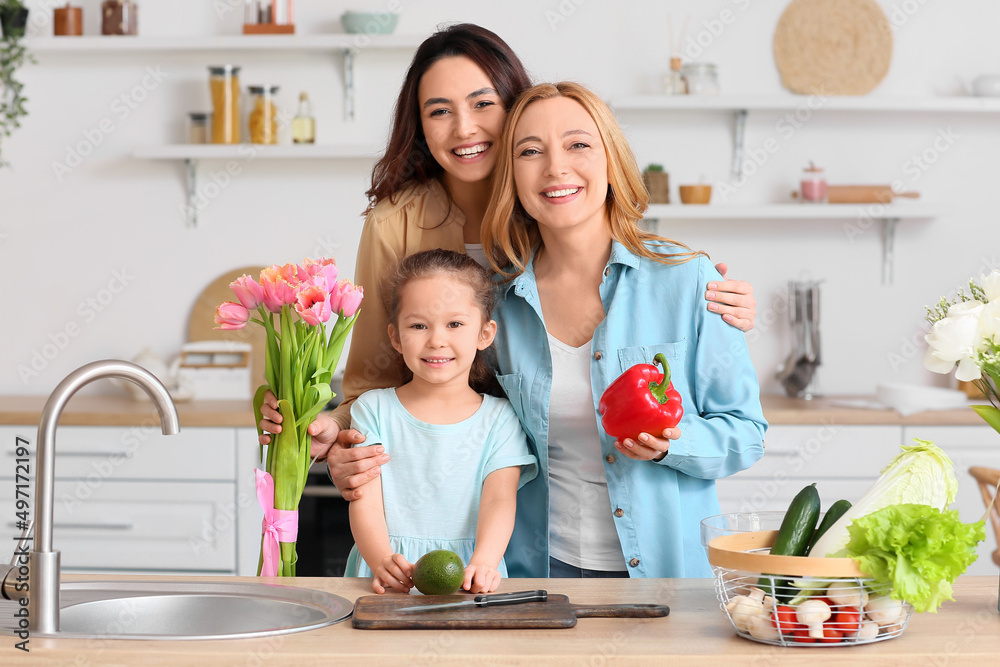 Happy young woman, her little daughter and mother in kitchen at home. International Women's Day celebration