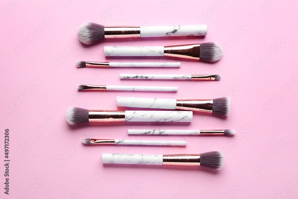 Set of makeup brushes on pink background, top view Set of makeup brushes on pink background, top view