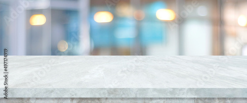 Empty white table top, counter, desk over blur perspective store with bokeh light background, White marble stone table, shelf and blurred shop for food, product display mockup, template backdrop