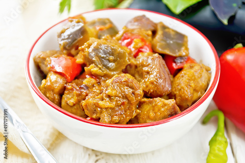 Meat with eggplant and pepper in bowl on board