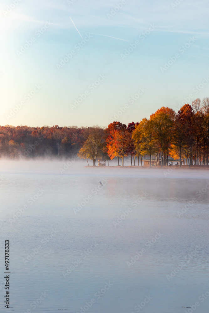 View of Blue Skies Along Foggy Lake with Trees with Fall Foliage 