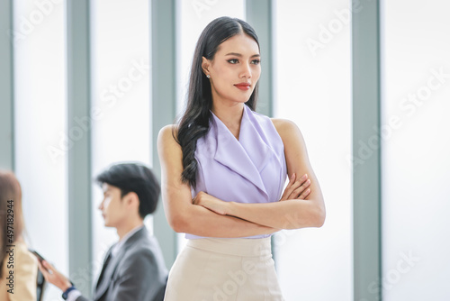 Millennial Asian young happy beautiful female businesswoman employee staff in formal business suit standing smiling hands posing in company office meeting room.