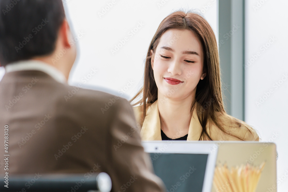 Asian young happy professional successful male and female businessman businesswoman in formal business suit sitting working talking discussing brainstorming together at workstation in meeting room Asian young happy professional successful male and female businessman businesswoman in formal business suit sitting working talking discussing brainstorming together at workstation in meeting room