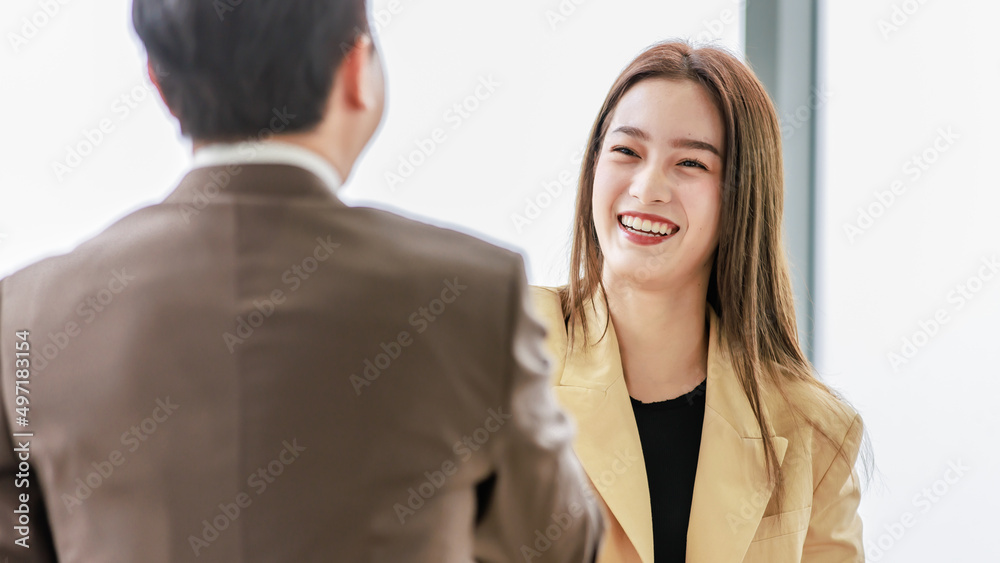 Closeup shot Asian young pretty confident professional successful businesswoman in formal business suit standing smiling shaking hands greeting with unrecognizable businessman in blurred foreground Closeup shot Asian young pretty confident professional successful businesswoman in formal business suit standing smiling shaking hands greeting with unrecognizable businessman in blurred foreground