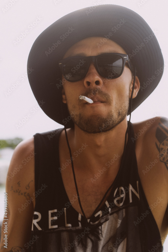 Obraz premium Man traveler in sunglasses and a hat with a cigarette.