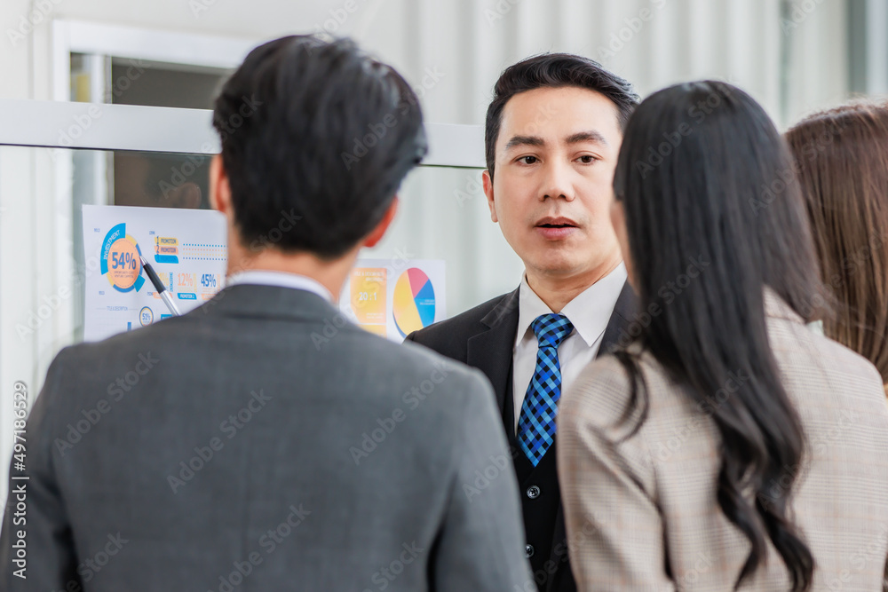 Asian happy male and female professional successful businessman and businesswoman colleagues partnership teamwork in formal business suit standing smiling look at post it note on glass board together Asian happy male and female professional successful businessman and businesswoman colleagues partnership teamwork in formal business suit standing smiling look at post it note on glass board together