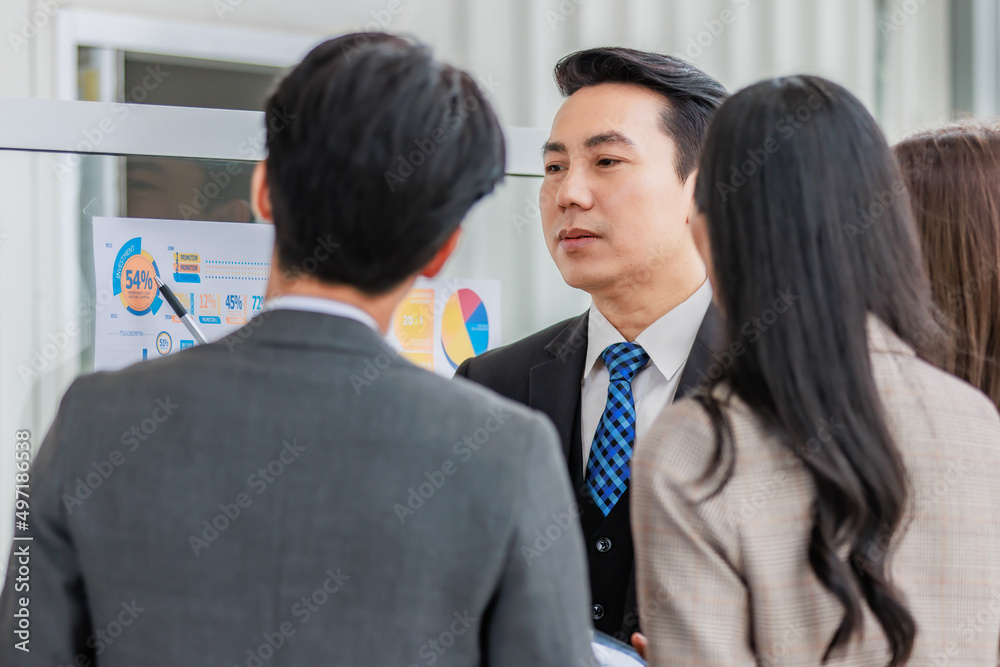 Asian happy male and female professional successful businessman and businesswoman colleagues partnership teamwork in formal business suit standing smiling look at post it note on glass board together