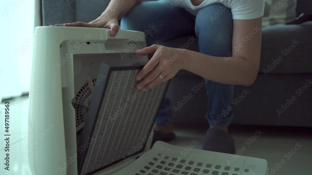 Woman changing the old used air purifier filter to the new one.