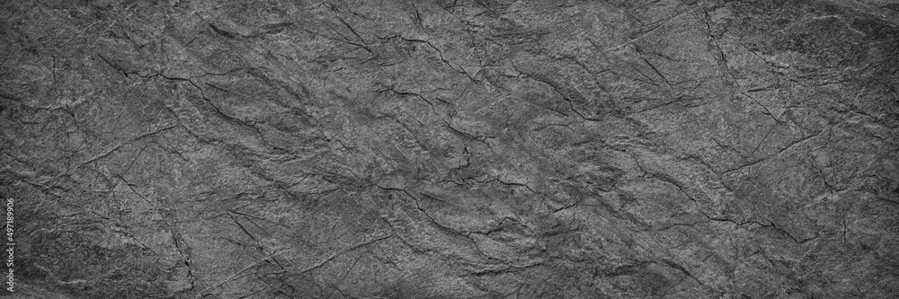 Black white rock texture. It looks like a rough concrete wall surface. Dark gray stone grunge background with space for design. Wide banner. Panoramic. Backdrop.