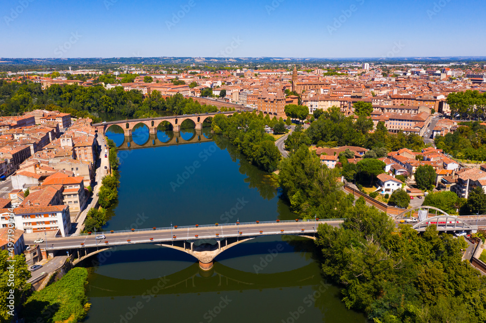 Scenic aerial view of French commune of Montauban on sunny summer day looking out over arched Old Bridge across Tarn river..