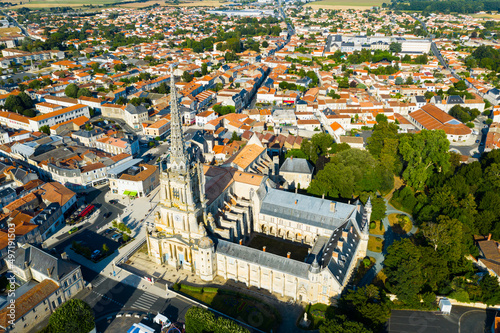 View from drone of houses and ancient Roman Catholic Cathedral of Lucon town at summer day, France