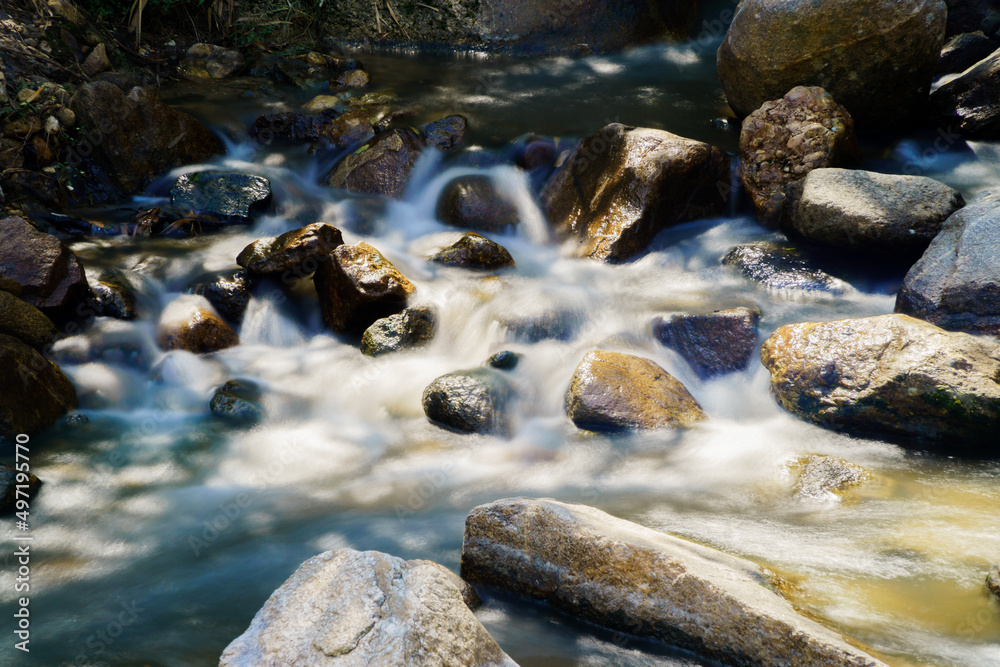Fototapeta premium Water flowing along rocks in nature, waterfall