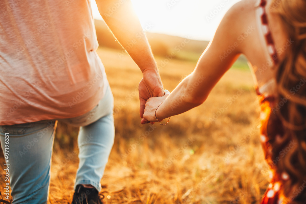 Couple holding hands and walking on golden wheat field over beautiful sunset. Summer vacation. Autumn landscape. Family concept. Nature landscape. Couple holding hands and walking on golden wheat field over beautiful sunset. Summer vacation. Autumn landscape. Family concept. Nature landscape.