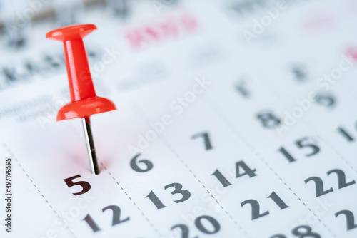 Red push pin on calendar 5th day of the month, mark the Event day with a Pin. Pin on calendar day five, date number 5. Fifth day of the month is marked with a red thumbtack