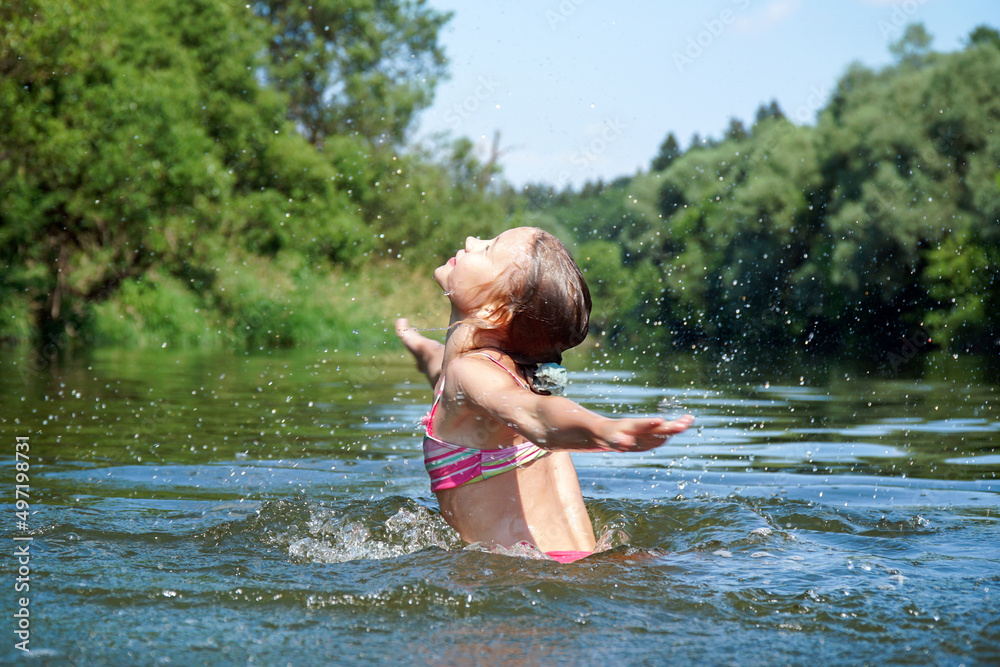Fototapeta premium The girl swims in the river in the summer. Splashes