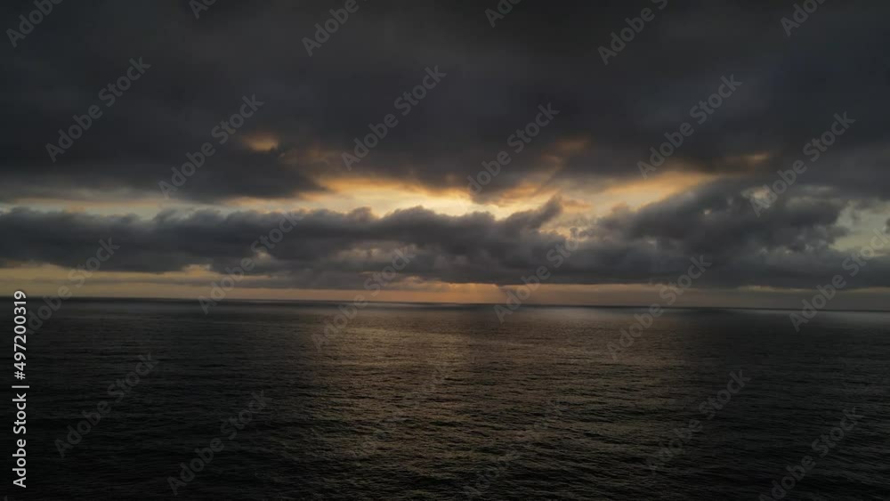 Sunset over the pacific ocean on a dark gloomy day with sun rays beaming through the thick dark clouds Sunset over the pacific ocean on a dark gloomy day with sun rays beaming through the thick dark clouds