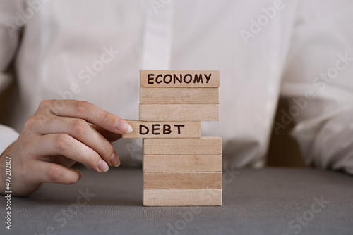 Close-up hand takes one block on a wooden block tower, Debt risk photo