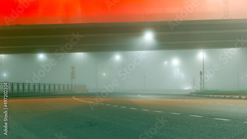 View of a multi-lane road in the fog under the illuminated bridge. Foggy city road. © Vladislav Fokin