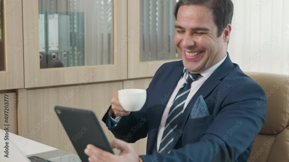 Happy business man reading news on his tablet he smiling, businessman working alone at his desk in an office workspace holding digital tablet Happy business man reading news on his tablet he smiling, businessman working alone at his desk in an office workspace holding digital tablet