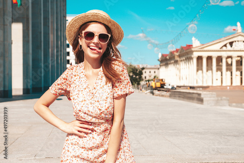 Young beautiful smiling hipster woman in trendy summer clothes. Sexy carefree woman posing on the street background at sunset. Positive model outdoors. Cheerful and happy in sunglasses and hat © halayalex