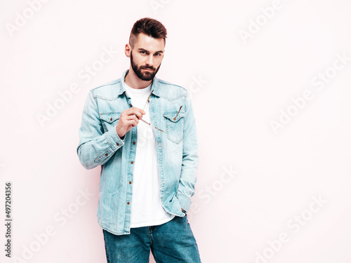 Portrait of handsome confident stylish hipster lambersexual model.Man dressed in jacket and jeans. Fashion male posing in studio in sunglasses. Isolated