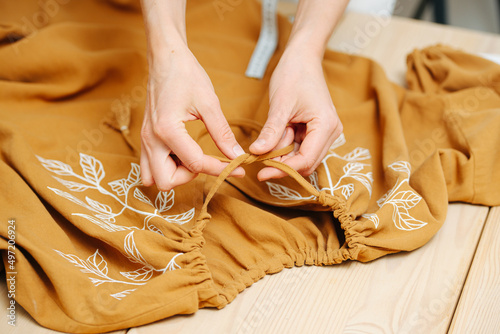 Zoomed in image of seamstress hands lacing a dress