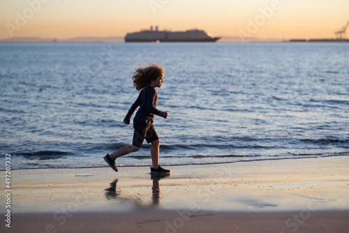 Kid running on beach. Happy child run in sea on summer vacation. Summer vacation with child.