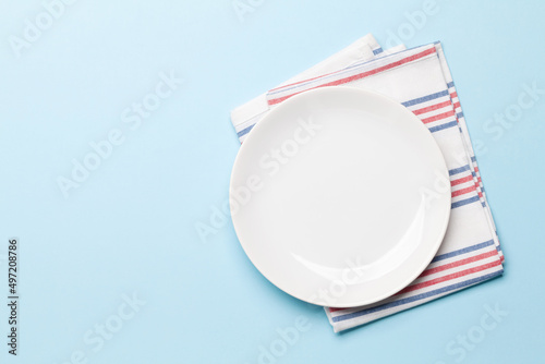 Empty plate and towel on blue background
