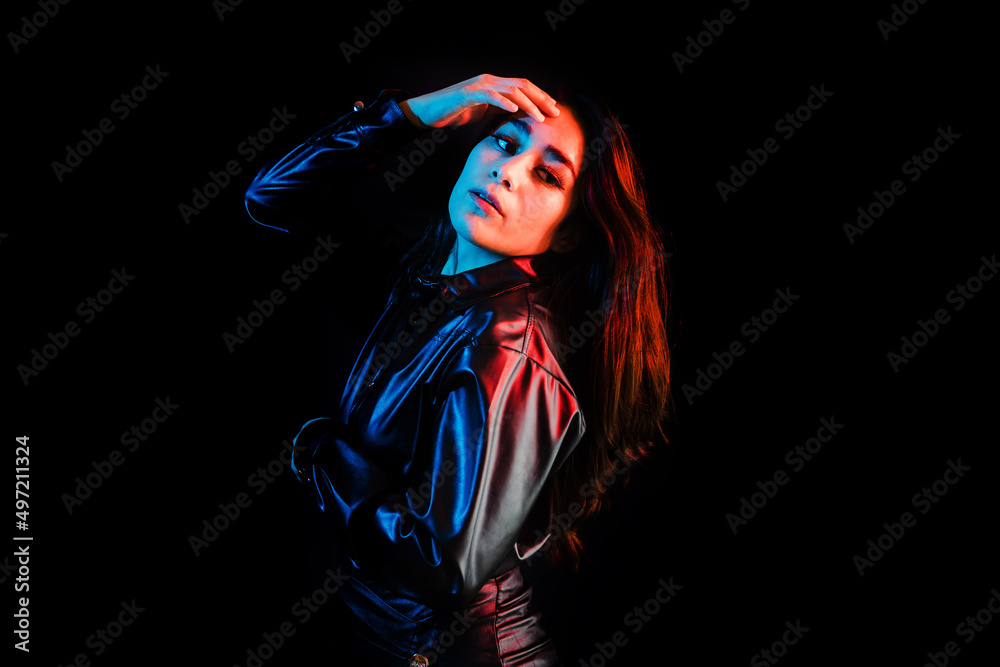 young latin woman dressed in black clothes with colorful pink-blue lights on black background in Mexico Latin America