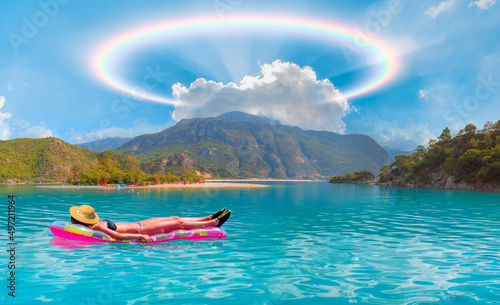 Girl in bikini lying on air bed -    Oludeniz Beach And Blue Lagoon with rounded rainbow - Oludeniz beach is best beaches in Turkey - Fethiye, Turkey photo