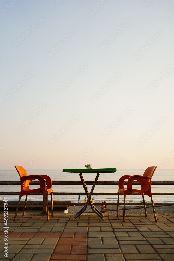 Orange plastic chairs with furniture at the seaside terrace with sky on background